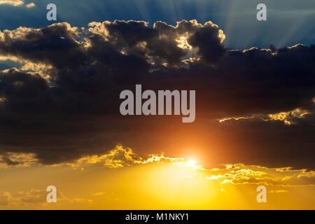 The sun hid behind black clouds and its rays beat up. Stock Photo