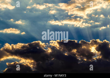 The sun hid behind black clouds and its rays beat up. Stock Photo