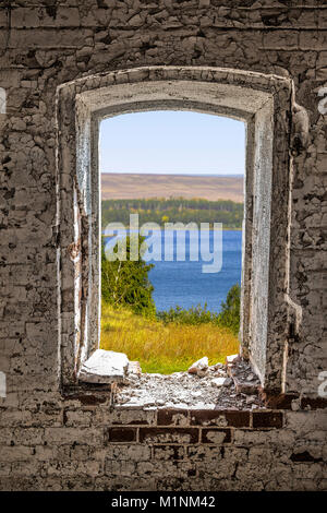 A view from a window hole of an old dilapidated abandoned house. Stock Photo