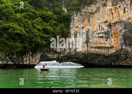Young women posing on a rowboat outside a cave in Halong Bay, Vietnam. The islets and limestone cliff formations have become a UNESCO protected area. Stock Photo