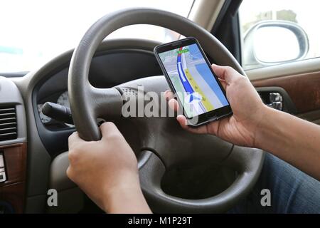 Man using his mobile phone to navigate with map application while driving. Dangerous driver. Concept and idea of safety driving Stock Photo
