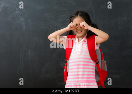 pretty young female kid children dislike studying standing in chalkboard background crying when she need back to school learning. Stock Photo