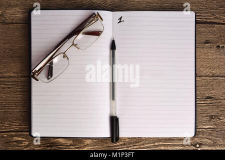 Wood table with blank notepad, pen and glasses. Open notebook with glasses and pen. Copy space for text. Stock Photo