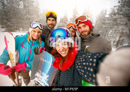 Group of happy friends having fun on the snow. Snowboarders and skiers making selfie Stock Photo
