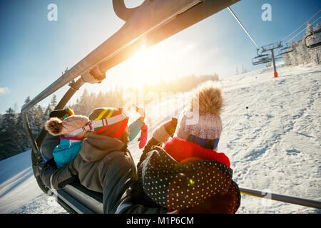 friends skiers and snowboarders on ski lift in the mountain at winter vacations back view Stock Photo
