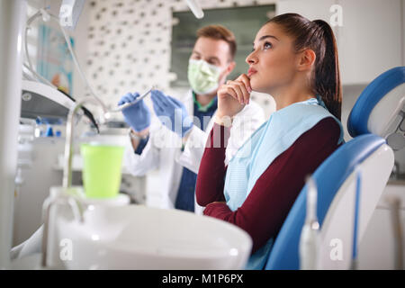 Worried young female waiting in dental chair for repairing her painful tooth Stock Photo