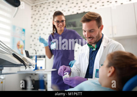 Dentist shows to girl in dental ordination how to brush her teeth Stock Photo