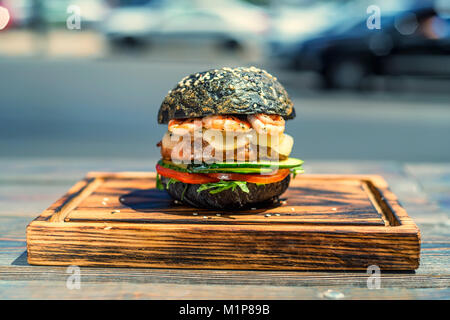Black burger with prawns on wooden board Stock Photo