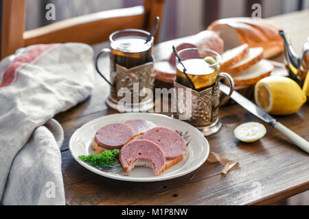 Sandwiches with sliced sausage on a plate with tea Stock Photo