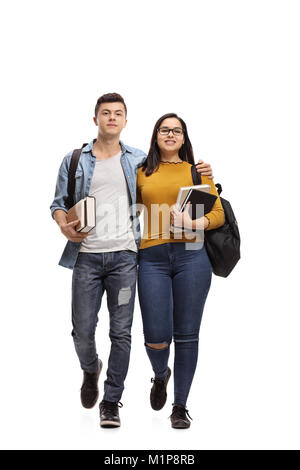 Full length portrait of two teenage students with backpacks and books walking towards the camera isolated on white background Stock Photo