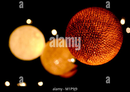 Macro shot of colorful Christmas decorations. Light bulbs made of yarn threads. Orange and warm yellow romantic night lanterns on dark background Stock Photo