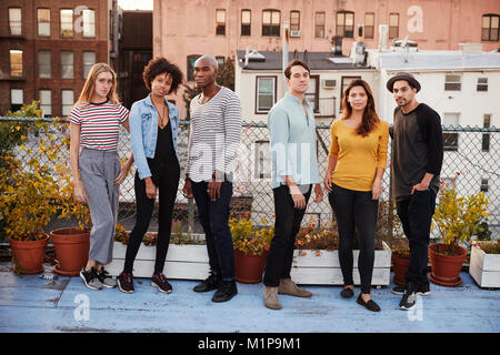 Six adult friends standing together on rooftop, full length Stock Photo