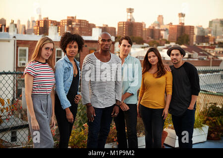 Six adult friends standing together on a Brooklyn rooftop Stock Photo