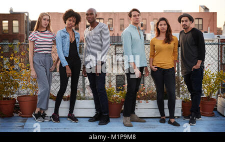Six adult friends standing together on rooftop, full length Stock Photo