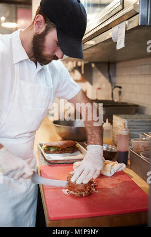 Man in butcher's shop preparing food for customer, vertical Stock Photo