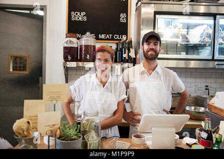Man and woman ready to serve behind the counter at butcher's Stock Photo