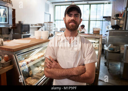 Young bearded butcher smiling to camera in his shop Stock Photo