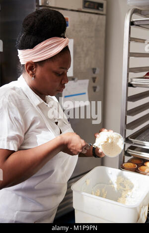 Young black woman at a bakery preparing cake frosting Stock Photo
