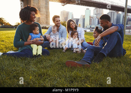 Two families with daughters sitting on lawn Stock Photo