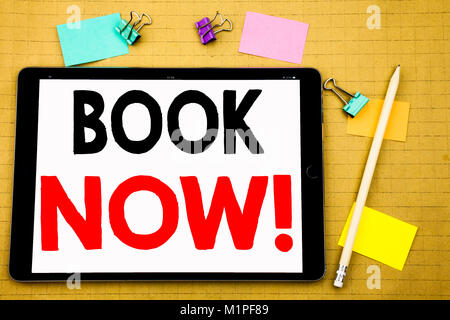 Hand writing text caption inspiration showing Book Now. Business concept for Reservation Booking Written on tablet, wooden background with sticky note Stock Photo