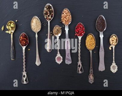 Spices in spoons on black stone background, top view Stock Photo