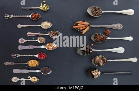 Spices in spoons on black stone background, top view Stock Photo