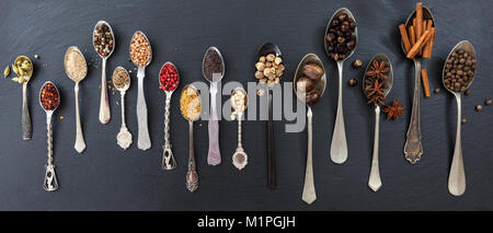 Spices in spoons on black stone background, top view, banner Stock Photo