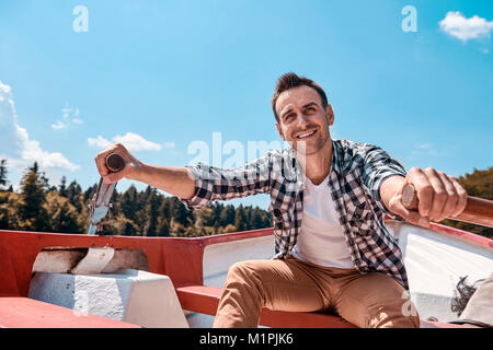 Man sitting in canoe and sailing on lake Stock Photo