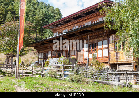 Bumthang, Bhutan.  Rural Farmhouse near Jakar.  Colored Prayer Flag in Front. Stock Photo