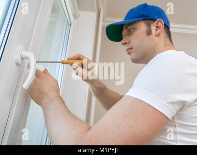 Professional handyman fixing window handle at home. Stock Photo