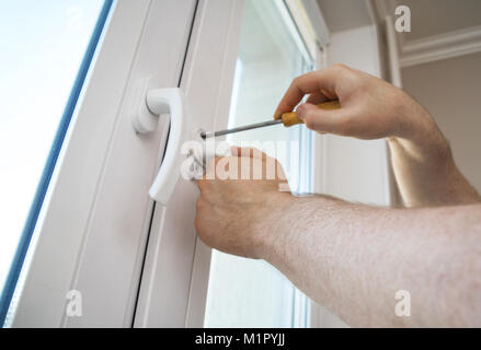 Professional handyman fixing window handle at home. Stock Photo