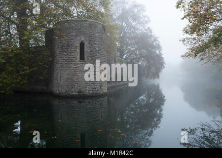 A defensive tower forming the ramparts of the Medieval Bishop's Palace and moat shrouded in thick fog on a November morning, Wells, Somerset, England. Stock Photo