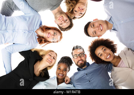 Group Of Smiling College Students Forming Huddle Against White Background Stock Photo