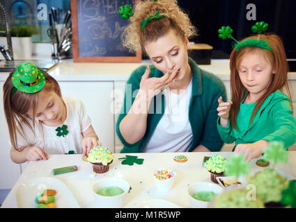 Mother with children decorating cupcakes at kitchen Stock Photo