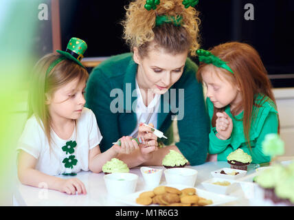 Interested children decorating cupcakes with mother Stock Photo