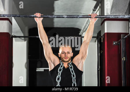 Athlete Man Wearing A Metal Chain Doing Pull-ups On Horizontal Bar In The Gym Stock Photo