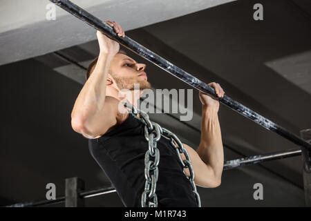 Athlete Man Wearing A Metal Chain Doing Pull-ups On Horizontal Bar In The Gym Stock Photo