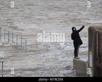 Sheerness, Kent, UK. 1st Feb, 2018. UK Weather: a young woman takes a surge tide selfie as the Neptune Jetty is covered by water during today's surge tide. Sunny spells but with a strong and cold westerly wind. Credit: James Bell/Alamy Live News Stock Photo