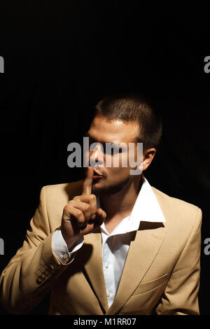 Portrait of businessman showing silence gesture with his forefinger by mouth Stock Photo