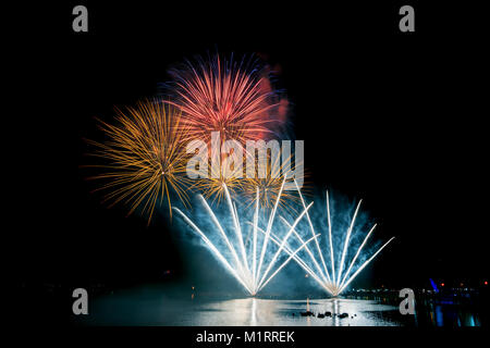Bright and colorful fireworks against a black night sky.Fireworks for new year. Beautiful colorful fireworks display on the urban lake for celebration Stock Photo