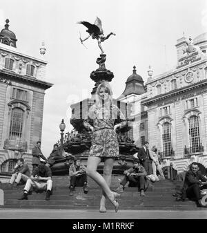 A model poses in a mini dress outdoors in London's Piccadilly near the statue of Eros in circa 1968 wearing a colourful mini-dress.   Photo by Tony Henshaw Stock Photo