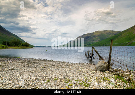 A fence runs into the Wastwater Lake, the deepest in England, and surrounded by some of the highest mountains in the country. Lake District, Cumbria. Stock Photo