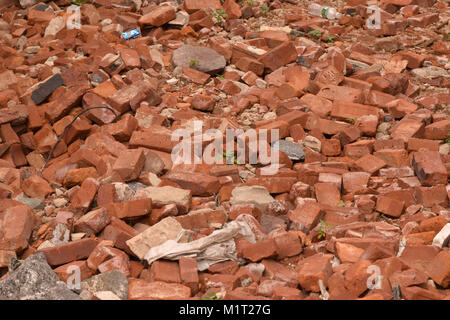 Pile of red bricks and debris with weeds close up abstract texture background. Stock Photo
