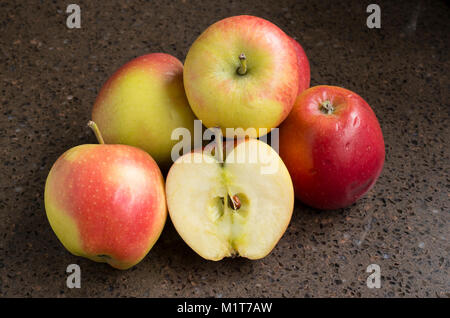 Selection of shop-bought Kansi apples variety Nicoter characterised by coloour, taste and crispness with one sliced in half to show the clean flesh in Stock Photo