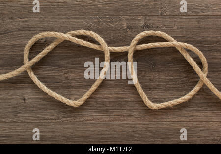 Two heart ropes connected to a knot on an old wood Stock Photo