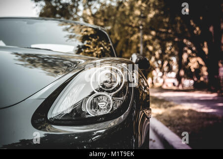 Headlight of silver sleek, luxury car parked on the street. Stock Photo