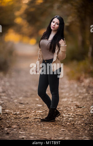 Beautiful Young Woman waering casual clothes posing in the forest, full body shot with extreme shallow Depth of Field Stock Photo