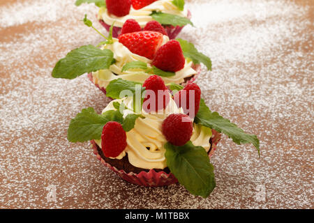 Homemade delicious chocolate cupcakes with fresh raspberry and cream on top. Delicious cupcake for Valentine’s Day. Stock Photo
