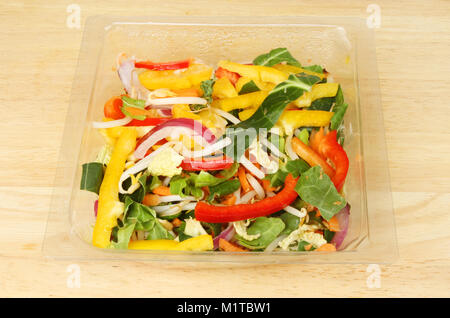 Stir fry vegetables in a plastic carton on a wooden chopping board Stock Photo