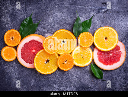 Different sliced citrus on dark concrete background Stock Photo